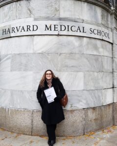 A Woman Stands Confidently in Front of the Harvard Medical School Sign